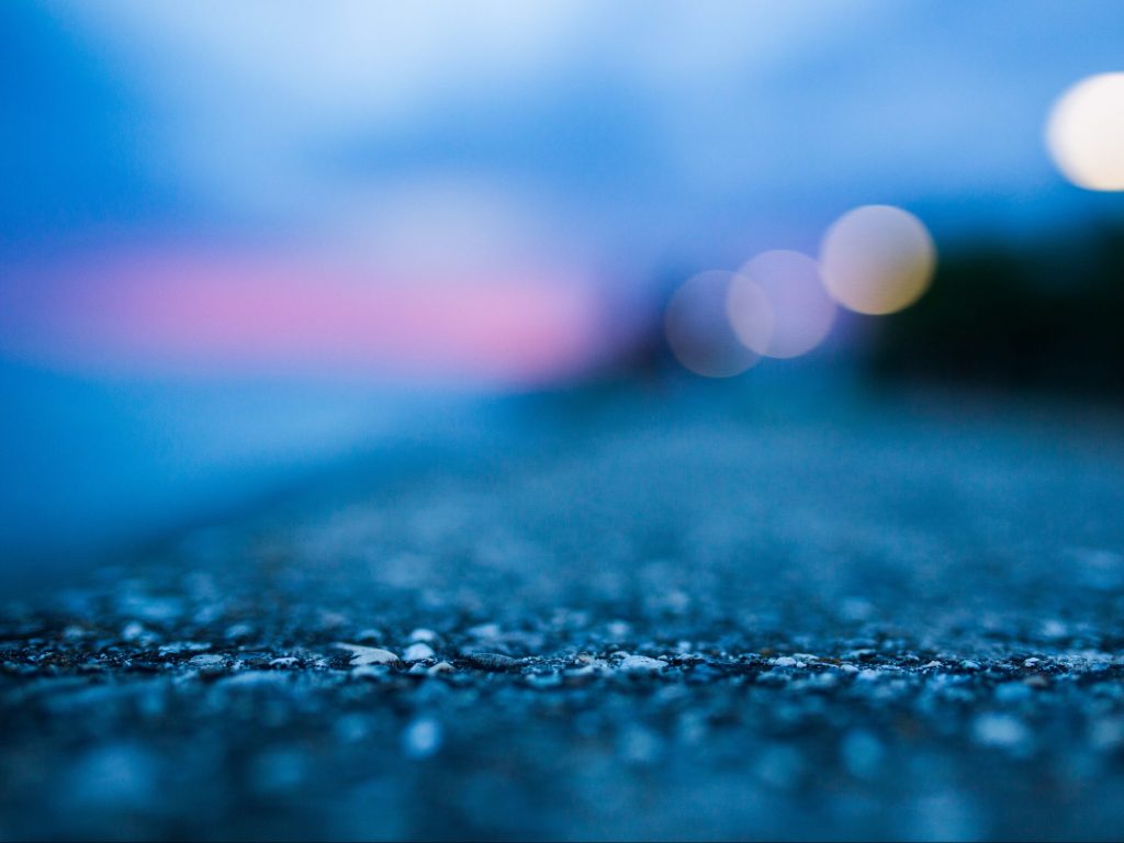 Close up image of a paved road with a blurry dark blue and pink background