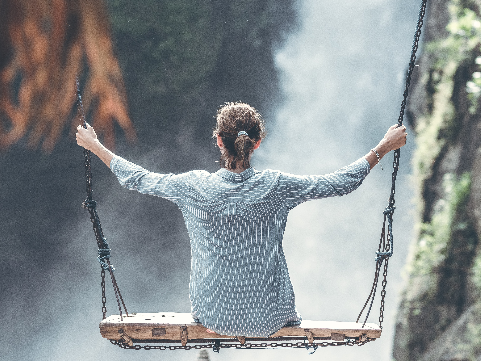 a woman sits on a swing with her back facing us