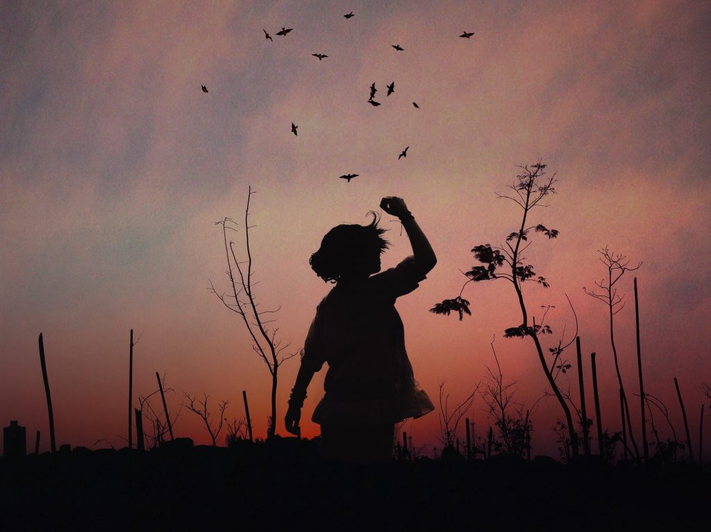 a profile of a woman standing in front of the sky at dusk