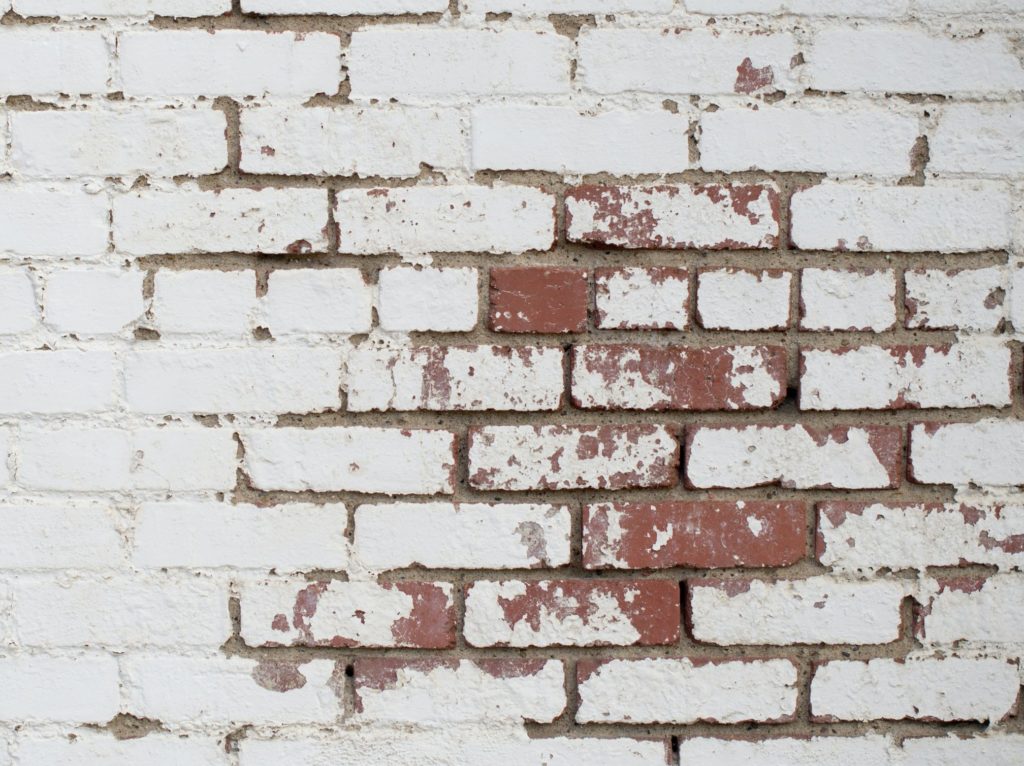 a white brick wall with some of the red brick showing through