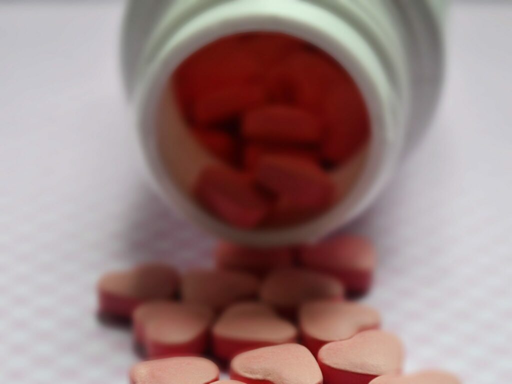 medicine bottle tipped over with heart-shaped pills scattered on the counter